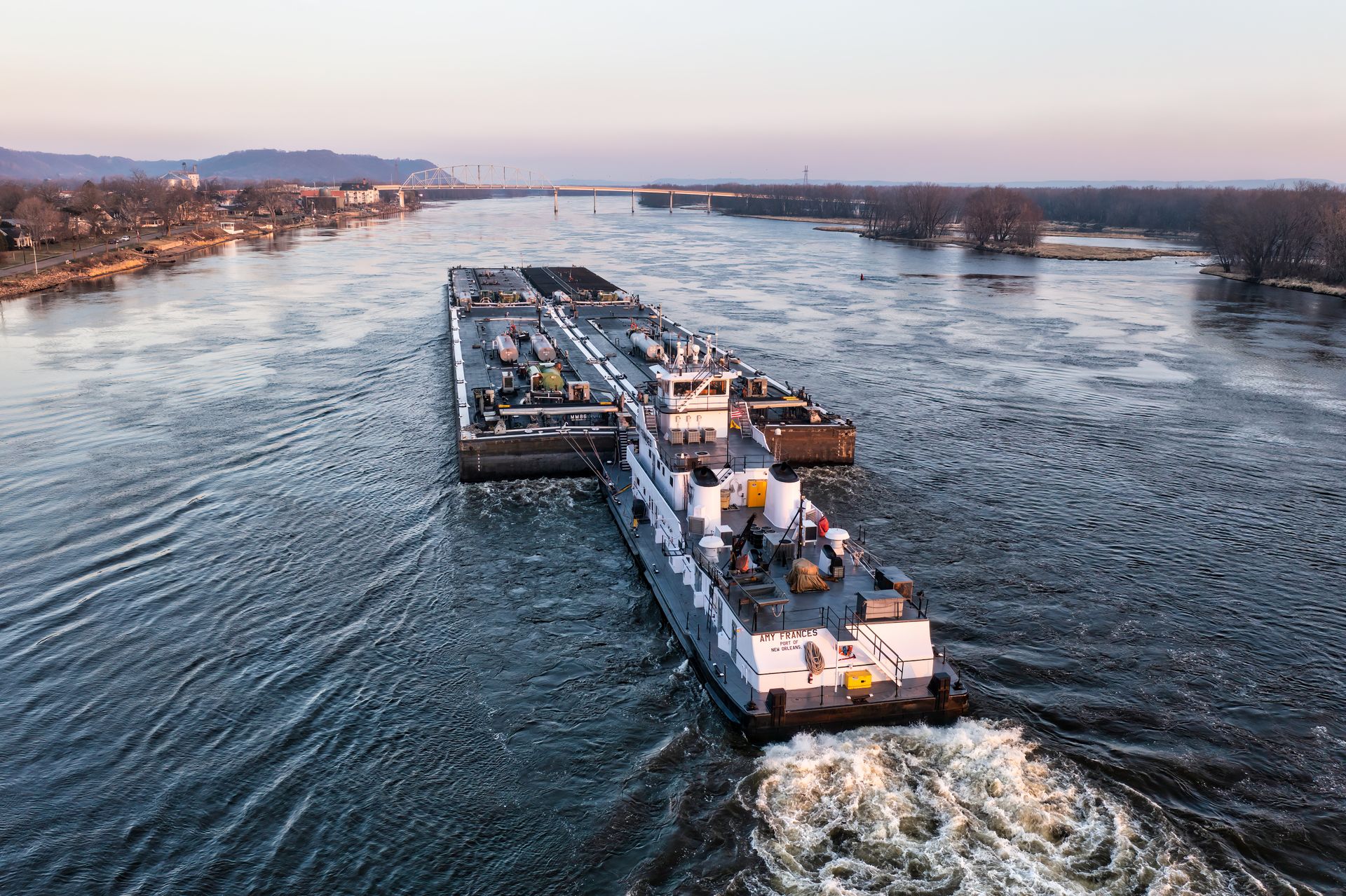 Convoy de barcazas tanque navegando un río al atardecer